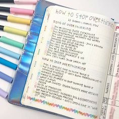 an open notebook with markers and writing on it next to some colored pens in the pages