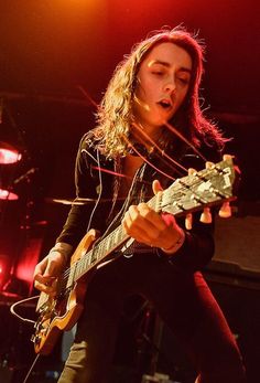 a woman playing an electric guitar on stage