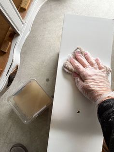 a person wearing gloves and holding a rag on top of a piece of white paper