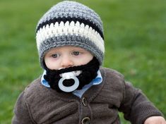 a baby wearing a knitted hat with a pacifier in his mouth