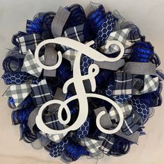 a monogrammed wreath with the letter f in white and blue ribbon on it