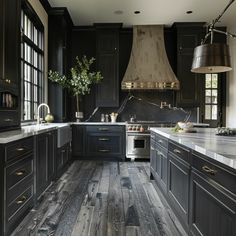 a large kitchen with black cabinets and wood flooring is seen in this image from the front