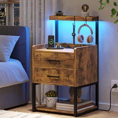 a night stand with headphones on it next to a bed in a room that has a blue light