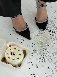 a woman's legs with high heels and a cake in a container on the ground