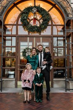 a man and two children standing in front of a building with wreaths on it