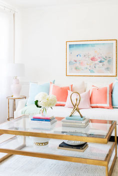 a living room with white couches and colorful pillows on the coffee table in front of it