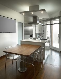 a kitchen with an island and stainless steel appliances in the center, along with wooden flooring