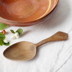 a wooden spoon sitting on top of a white cloth next to a bowl with flowers