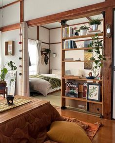 a living room filled with furniture and bookshelves in front of a bed next to a window