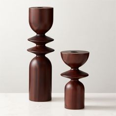 two wooden candlesticks sitting next to each other on top of a white table