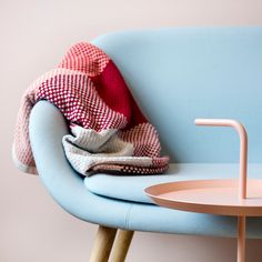 a blue chair with a red and white checkered blanket on it next to a round table