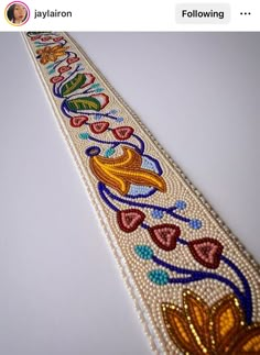 a beaded bracelet with flowers and hearts on it's side, sitting on top of a table