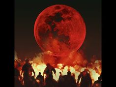 a group of people standing in front of a giant red moon