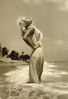 a woman is standing in the water at the beach