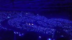 a large group of people standing in front of a stage with blue lights on it