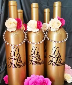 four gold bottles with pink and white flowers on them