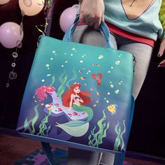 30% OFF Available now in our shop is the 35th Anniversary collection of The Little Mermaid! "Life is the Bubbles" is the theme, featuring an ocean scene of Ariel, Ursula, Flounder, and Sebastian under the the castle. This tote bag is a brand new style from Loungefly! You'll love the bright, printed & applique details, and the front, scalloped wave-shaped zippered compartment. And parts of the design glow in the dark! Tote bag is made of vegan/faux leather with silver-toned metal hardware, remova Disney School Bags In Rectangular Shape, Disney School Bag With Adjustable Strap, Blue Rectangular Bag For Disney Trips, Disney Rectangular Travel Bag, Blue Disney Bags For Gifts, Disney Travel Bags With Detachable Strap, Disney Style Daily Backpack, Disney Backpack For Everyday Use, Disney Style Backpack Bag For Gifts