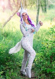 a woman dressed as a unicorn posing in the woods with her arms up and legs spread out