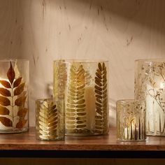 candles are lined up on a shelf with leaves in them