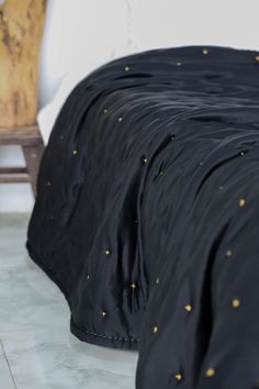 a black comforter with gold stars on it and a wooden chair in the background