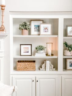 a white bookcase with pictures and plants on it