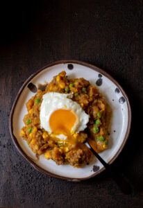 a white plate topped with meat and an egg on top of it next to a fork