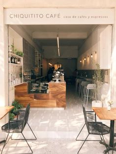 the inside of a restaurant with tables and chairs in front of it, next to an open door