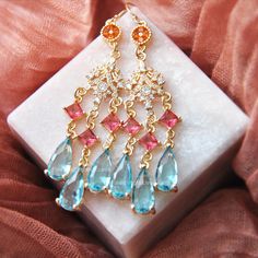 Make a statement this summer with these colorful earrings created with 14k gold filled earrings for a comfortable all day wear! Suspended from the statement earrings are light aqua blue teardrops accented with princess cut magenta pink faceted glass and tiny cubic zirconia charms. Whether searching for whimsical wedding earrings for your special day or a unique chandelier earrings, or a birthday gift for a best friend, all of my jewelry arrives suitably gift wrapped ready for gift giving. Measur Blue Dangle Chandelier Earrings For Celebration, Blue Dangle Earrings For Celebration, Blue Dangle Bridal Earrings For Celebration, Blue Dangling Beads Earrings For Celebration, Blue Drop Earrings For Bridal Celebration, Blue Drop Bridal Earrings For Celebration, Blue Dangling Beads Earrings For Wedding, Blue Wedding Earrings With Dangling Beads, Elegant Multicolor Jeweled Chandelier Earrings