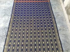 a black and orange rug sitting on top of a stone floor next to a wall