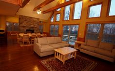 a living room filled with furniture next to a fire place and large window covered in wooden beams