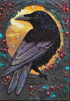 a black bird sitting on top of a table next to red and blue beads in front of a full moon