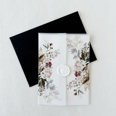 a white and black card with flowers on it next to a wax stamp that says love