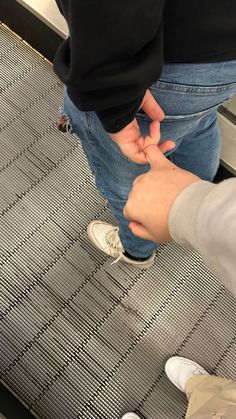 two people are standing on an escalator and touching their hands with each other