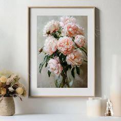 a bouquet of pink peonies in a vase on a white shelf next to a candle