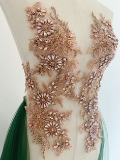 the back of a dress with gold flowers on it and green tulle around the waist