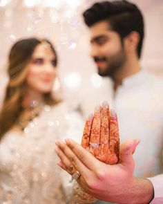 a man and woman standing next to each other holding something in front of their face