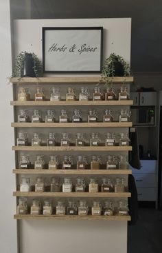 shelves filled with jars and spices on top of each other in front of a white wall