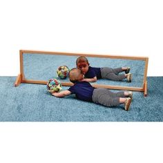 two children laying on the floor in front of a mirror