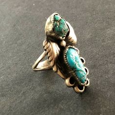 "VINTAGE NAVAJO RING DESCRIPTION: This gorgeous ring is by legendary Navajo artisan David K Lister. Two breathtaking specimens of natural turquoise are secure in micro serrated bezel, flanked by applied leaves, on a foundation oh heavy gauge vintage sterling silver. PLEASE NOTE that the larger of the two cabs has a hairline fissure. The turquoise is secure in its setting. This ring will be a treasured addition to your collection of fine vintage Native American jewelry. MEASUREMENTS: Ring face me Antique Turquoise Ring With Patina, Heirloom Turquoise Ring For Collectors, Artisan Rings With Patina For Collectors, Turquoise Ring With Patina For Anniversary, Anniversary Turquoise Ring With Patina, Vintage Sterling Silver Turquoise Ring, Vintage Turquoise Oval Ring, Vintage Untreated Oval Emerald Ring, Vintage Oval Untreated Emerald Ring