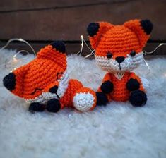 two crocheted stuffed animals sitting next to each other on a white rug with string lights