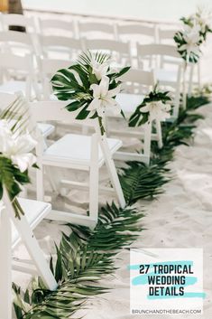 white chairs lined up on the beach with flowers and greenery