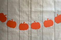 orange pumpkins cut out on a white wood background with the word fall written across them