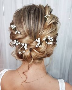 the back of a woman's head with flowers in her hair, wearing a white dress