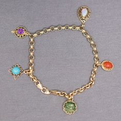 "Multi-Gemstone Dangling Charm Bracelet on Rolo Chain in 14k Yellow Gold This pretty and playful charm bracelet features five stations with gemstone charms, each different and set in their own gold mountings.  The opal charm features a 8.59 x 5.75mm natural opal, the coral in the coral charm measures about 8.47 x 5.50mm, the jade in the jade station measures about 10.5mm in diameter, the turquoise in the turquoise station measures about 6.5mm, and the amethyst measures about 6.2mm.  The stones a Yellow Gold Charm Bracelet With Dangle Shape, 14k Gold Charm Bracelet With Dangling Charms For Gift, Yellow Gold Charm Bracelet With Dangling Charms, Yellow Gold Charm Bracelet Fine Jewelry, 14k Gold Charm Bracelet With Dangling Charms As Gift, Fine Jewelry Yellow Gold Charm Bracelet, 14k Yellow Gold Charm Bracelet With Dangling Charms, Yellow Gold Fine Jewelry Charm Bracelet, 14k Gold Jewelry With Gemstone Accents And Dangle Shape