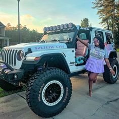 a woman standing next to a white jeep