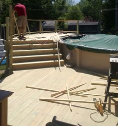 a man standing on top of a wooden deck next to an above ground swimming pool