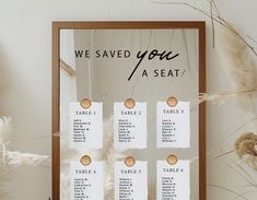 the seating chart for a wedding is displayed in front of some dried flowers and feathers