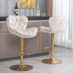 two white and gold bar stools in front of a counter with bottles on it