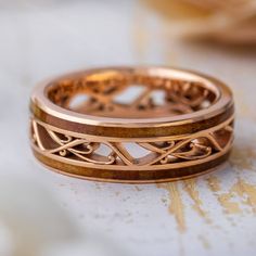 two wedding bands made out of copper and wood with intricate designs on the sides, set against a white background