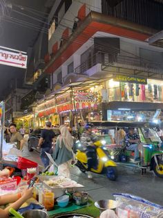 an outdoor food market with people shopping and eating at tables in front of the building